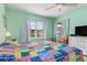Light-filled bedroom showcasing a colorful patchwork quilt, dresser with a TV, and windows at 5725 Greenwood Ave # 8203, North Port, FL 34287