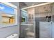 Modern bathroom features a glass shower door, gray tiles, and a window for natural light at 7183 Spinnaker Blvd, Englewood, FL 34224
