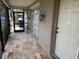 Covered entryway featuring a tiled floor, brick accent wall, and a charming vintage lantern at 8158 Trionfo Ave, North Port, FL 34287