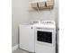 Well-equipped laundry room featuring a modern washer and dryer and a storage shelf at 8866 Tuscany Isles Dr, Punta Gorda, FL 33950