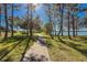 Scenic lakeside walking path shaded by trees, inviting leisurely strolls with serene water views at 8866 Tuscany Isles Dr, Punta Gorda, FL 33950