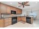 Well lit kitchen featuring wood cabinets, tile backsplash, black appliances, and granite counters at 1 Colony Point Dr # B20, Punta Gorda, FL 33950