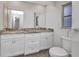 Bathroom featuring double vanity, granite countertops, white cabinets, toilet, and arched window at 1210 Mccrory St, North Port, FL 34286