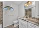 Bathroom with marble countertop, single vanity, toilet, decorative wall mirror, and arched window at 1210 Mccrory St, North Port, FL 34286