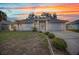 Well-maintained single-story home featuring a screened entry and attached two-car garage at sunset at 1210 Mccrory St, North Port, FL 34286
