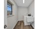 Bright laundry room with wood-look floors, utility sink, and window at 1210 Mccrory St, North Port, FL 34286