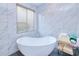 Modern bathroom featuring freestanding tub, large window, and marble tile walls at 13295 Eisenhower Dr, Port Charlotte, FL 33953