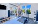 Bright home gym featuring modern exercise equipment, blue tile flooring, mirrored closet doors, and natural light from the window at 13295 Eisenhower Dr, Port Charlotte, FL 33953