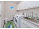Bright laundry room featuring a sink, granite countertops, washer, dryer, and ample white cabinet storage at 13295 Eisenhower Dr, Port Charlotte, FL 33953