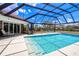 A beautiful pool with surrounding lounge areas, greenery, and seating, inside of a screened-in enclosure at 13295 Eisenhower Dr, Port Charlotte, FL 33953