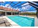 A large screened-in pool featuring lounge chairs and a dining table offering ample space for relaxation and entertainment at 13295 Eisenhower Dr, Port Charlotte, FL 33953