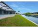 Beautiful waterfront backyard with a screened lanai, grassy lawn, and private canal access at 15148 Taurus Cir, Port Charlotte, FL 33981