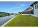 Waterfront home featuring a screened lanai with a canal and lush green lawn at 15148 Taurus Cir, Port Charlotte, FL 33981