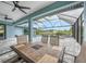 Inviting screened-in patio with a dining table, ceiling fans, and a view of the pool and canal at 15148 Taurus Cir, Port Charlotte, FL 33981