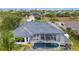 Aerial view of a single-story home featuring a screened-in pool area and dark roof at 15890 Viscount Cir, Port Charlotte, FL 33981