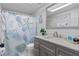 Bathroom features a gray vanity with stone top, framed mirror, and tub-shower combo with seashell shower curtain at 15890 Viscount Cir, Port Charlotte, FL 33981
