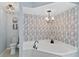Relaxing bathroom featuring a soaking tub with a modern chandelier and wallpaper at 15890 Viscount Cir, Port Charlotte, FL 33981