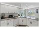Bright kitchen features white cabinets, granite countertops, and views of the pool and canal at 15890 Viscount Cir, Port Charlotte, FL 33981