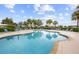 Community pool surrounded by lounge chairs, tables, and tropical palm trees at 2747 Suncoast Lakes Blvd, Punta Gorda, FL 33980