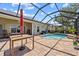 A screened-in pool featuring brick pavers, a red umbrella, and a blue spa is perfect for entertaining at 2747 Suncoast Lakes Blvd, Punta Gorda, FL 33980