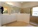 Bathroom featuring double sink, large mirror and walk in shower behind half wall at 3772 Peace River Dr, Punta Gorda, FL 33983