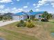 Single-story home showcasing a bright blue metal roof, lush landscaping, and a well-manicured lawn at 3825 Barnegat Dr, Punta Gorda, FL 33950