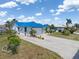 Charming home exterior featuring a blue roof, paved driveway, lush landscaping, and attached garage at 3825 Barnegat Dr, Punta Gorda, FL 33950