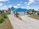 Attractive home featuring a blue metal roof, lush landscaping, and a spacious driveway at 3825 Barnegat Dr, Punta Gorda, FL 33950