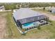 An aerial view of the home featuring a screened-in pool and patio area, surrounded by lush landscaping at 5061 Collingswood Blvd, Port Charlotte, FL 33948