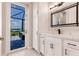 Bright bathroom featuring white cabinets, black fixtures, and view of outdoor living space at 5061 Collingswood Blvd, Port Charlotte, FL 33948