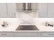 Close up of a kitchen cooktop and a white marbled backsplash with custom cabinetry and stainless fixtures at 5061 Collingswood Blvd, Port Charlotte, FL 33948