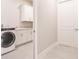 Laundry room with white cabinets, gray tile floors, and front load washer/dryer at 5061 Collingswood Blvd, Port Charlotte, FL 33948