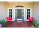 Cozy front porch featuring a gray door, red chairs, and potted plants creating an inviting entrance at 5219 Guava Ter, Port Charlotte, FL 33981
