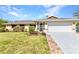 Inviting single-story home featuring lush green lawn, brick-lined driveway, and two-car garage at 566 Reading Nw St, Port Charlotte, FL 33952