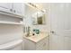 Well lit bathroom featuring single sink vanity, white cabinets, large mirror, and standard toilet at 6103 Fabian Rd, North Port, FL 34287