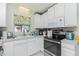 Bright kitchen with white cabinets, stainless steel appliances, and a window providing natural light, creating a clean and modern space at 6103 Fabian Rd, North Port, FL 34287