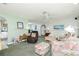 Open living room with archway access to kitchen, featuring plush armchairs, ceiling fan, and neutral walls at 6103 Fabian Rd, North Port, FL 34287
