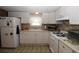 Compact kitchen featuring white cabinets, essential appliances, and a window offering natural light at 6843 Amoko Ct, North Port, FL 34287
