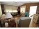 Cozy living room with wood paneling, comfortable seating, and natural light from the window with sheer curtains at 6843 Amoko Ct, North Port, FL 34287