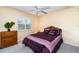 Cozy bedroom featuring a purple-themed bed, a dresser, neutral carpet, and a window with plantation shutters at 7101 Dogwood Ct, North Port, FL 34287