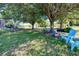 Large, grassy backyard with mature trees and blue chairs. Includes a distant view of a barn at 7274 Alan Blvd, Punta Gorda, FL 33982