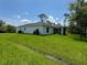 Large backyard with green grass and white house at 8687 Lisa Blvd, North Port, FL 34288