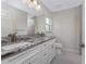 Bathroom featuring double vanity with granite countertop, white cabinets, and modern fixtures at 8687 Lisa Blvd, North Port, FL 34288