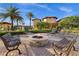 Stone fire pit with chairs and benches in an outdoor gathering area with beautiful landscaping and palm trees at 99 Vivante Blvd # 303, Punta Gorda, FL 33950
