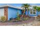 Inviting home exterior with a neatly landscaped garden, charming pathway, and vibrant blue facade at 10229 Gulfstream Blvd, Englewood, FL 34224