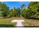A cozy home featuring a well-maintained backyard with a concrete pad, lush trees, offering a serene outdoor living space at 1231 Beacon Dr, Port Charlotte, FL 33952