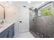 Bathroom featuring a glass-enclosed tiled shower, marble floors, double sink vanity, and modern lighting at 1231 Beacon Dr, Port Charlotte, FL 33952