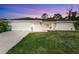 Charming single-story home featuring a two-car garage, manicured lawn, and freshly painted exterior at sunset at 1231 Beacon Dr, Port Charlotte, FL 33952