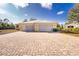 Yellow home with a three-car garage and a brick driveway at 13204 Kakapo Ave, Port Charlotte, FL 33981