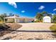 Charming yellow home featuring a three-car garage, brick driveway, and a separate storage shed at 13204 Kakapo Ave, Port Charlotte, FL 33981
